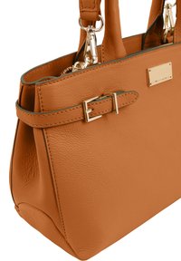 Sac à main en cuir tan avec une finition texturée, présentant un détail de boucle latérale proéminent et des accessoires en métal doré, de forme structurée et avec deux poignées.