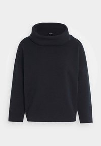 Musta, ylisuuri pörröpulloveri korkealla kauluksella, pitkät hihat ja pehmeä käyttö. Ominaisuuksiin kuuluu rento istuvuus sekä ei näkyviä kuvioita tai metalliosia.