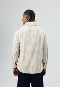 Corduroy overhemd met lange mouwen in licht beige met verticale strepen, voorzien van een kraag en knoopdetail op de manchetten.