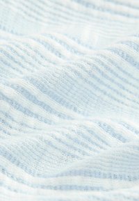 Helles blaues Strickgewebe mit weicher, gewellter Textur und sichtbaren feinen Garnschlingen im Nahaufnahme.