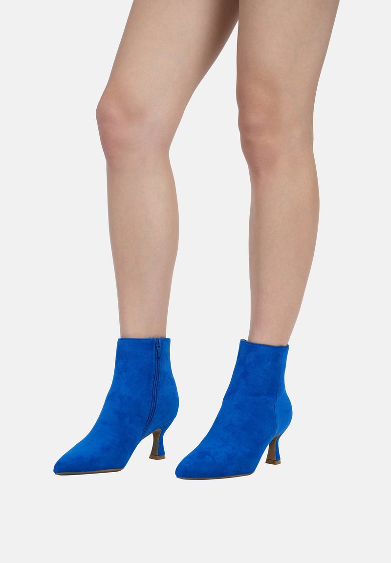 Botines de ante azules con punta afilada y un pequeño tacón, con cremallera lateral y textura suave.