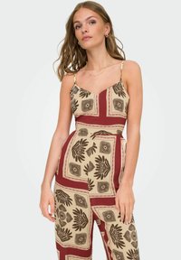 Une combinaison beige avec un motif floral et géométrique en marron et bordeaux, dotée de fines bretelles et d'un design décontracté.