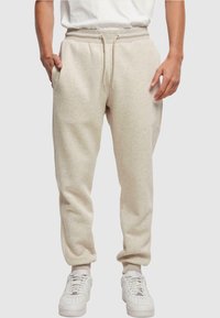 Beige joggingbroek met elastische tailleband en trekkoord. Zijzakken, taps toelopende benen en zachte stof. Gecombineerd met witte sneakers.