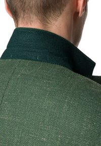 Zielona tkanina o fakturze z wysokim kołnierzem i widocznymi detalami przeszycia; materiał wydaje się solidny, ma miękkie wykończenie i delikatny połysk.