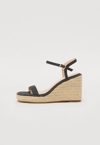 Mustad kangast nappjalatsid, millel on tekstuuriga espadrille-tald, avatud varvas ja pahkluupant, millel on kuldne pandla, kõrgus umbes 10 cm.