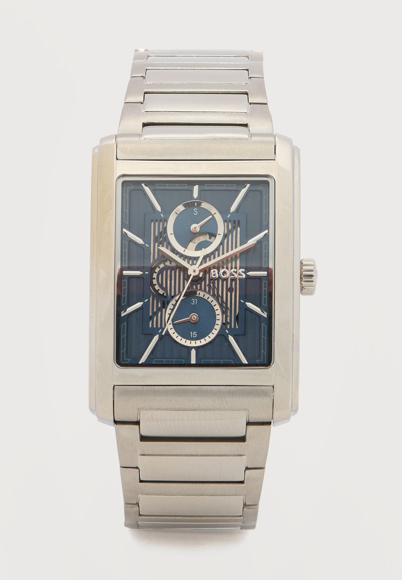 Ορθογώνιο ασημένιο μεταλλικό ρολόι χειρός με μπλε καντράν, τρεις υποκαντράν, ασημένιους δείκτες ώρας και λογότυπο "BOSS" σε μπρασελέ από συνδεδεμένα μεταλλικά στοιχεία.