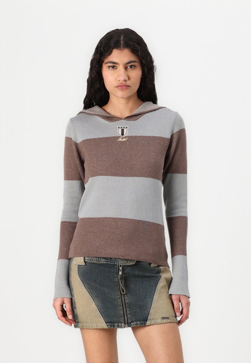 Maglione a strisce con cappuccio in grigio chiaro e marrone, con logo sul petto. Abbinato a una mini gonna in denim con pannelli a contrasto.