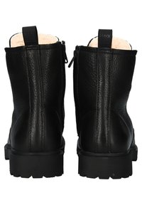 Paire de bottines en cuir noir avec doublure intérieure en polaire, languettes arrière, fermeture éclair latérale et semelles épaisses à crampons, vues de dos.