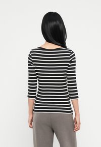 Svart og hvit stripet langermet topp med rund hals og trekvartlange ermer, laget av et mykt og elastisk stoff.