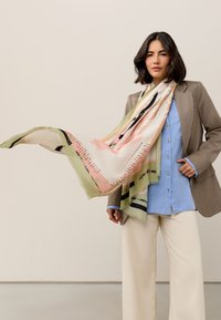 Sciarpa di seta in colori pastello con motivi astratti e accenti rosa, verdi e neri; bordi frangiati, design leggero e fluente.