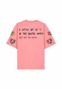 T-shirt rose avec texte noir et rouge « Un peu d'amour dans ce monde brutal (mais pas trop) » et motifs cœur, soleil, lèvres et cœur qui pleure.
