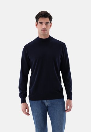 Marineblauer Rundhalsausschnitt-Pullover, gestrickte Textur, lange Ärmel, figurbetontes Design, kombiniert mit hellblauen Jeans. Minimalistisches Design, keine sichtbaren Logos.