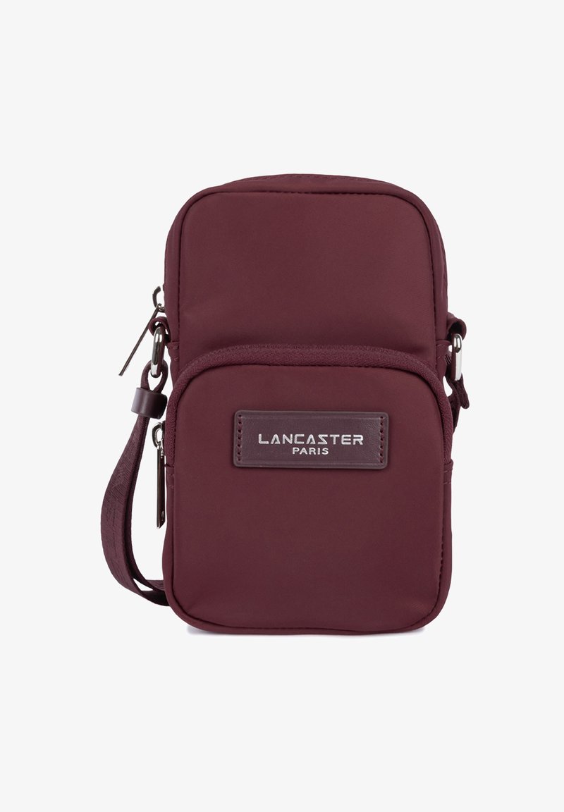 Sac bandoulière compact bordeaux avec poche zippée à l'avant et patch logo "Lancaster Paris", conçu pour un usage quotidien.