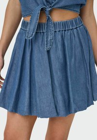 Lahka denim krila v srednje modri barvi, z elastičnim pasom in plastičnimi naborki za tekočo silhueto.