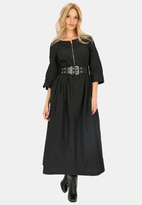 Czarna sukienka z długim rękawem, z zamkiem z przodu i ściągniętą talią, z szerokim czarnym paskiem z srebrnymi oczkami. Miękka, lekka tkanina.