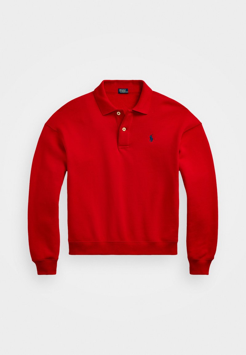 Röd polo sweatshirt i bomull. Har en kort krage med två knappar, ribbade muddar och en liten blå logotyp på vänster bröst.