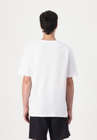 White cotton t-shirt with a relaxed fit, short sleeves, and a crew neck, viewed from the back. No visible patterns or accents.