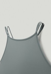 Szary, bezrękawnik z cienkimi ramiączkami i gładką fakturą. Projekt ma zaokrąglony dekolt i minimalne przeszycia.