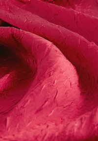 Textured fabric in vibrant crimson, featuring a slightly crinkled surface with a smooth sheen and rich folds. Ideal for upholstery or fashion.