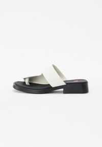 Vita läder slid sandal med ett brett rem, avsmalnande tåpost och en kraftig svart sula. Slät textur och minimalistisk design.
