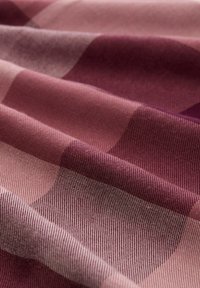 Tissu avec un motif ondulé dans des nuances de bordeaux et de rose, présentant une texture subtile et une finition tissée lisse. Forme rectangulaire.