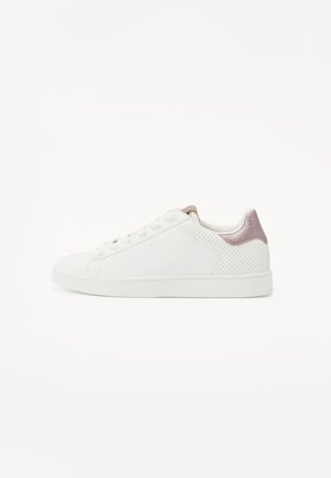 Zapatilla blanca de cuero suave con acentos perforados, cuenta con un talón en rosa claro y una suela de goma blanca plana. Diseño de cordones.