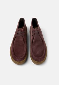 Burgunderfarbene Wildlederschuhe mit runder Zehenform, minimaler Schnürung und braunem Gummilaufsohle; mit kontrastierenden Nähten entlang der Kanten.