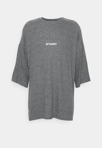 Harmaa ylisuuri T-paita, joka on valmistettu pehmeästä materiaalista. Siinä on pyöreä kaula-aukko ja lyhyet hihat. Rinnassa on valkoisella painettuna sana "STORM".