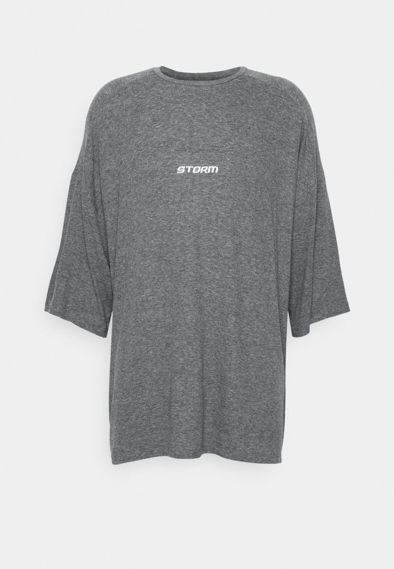 Harmaa ylisuuri T-paita, joka on valmistettu pehmeästä materiaalista. Siinä on pyöreä kaula-aukko ja lyhyet hihat. Rinnassa on valkoisella painettuna sana "STORM".