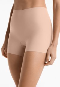 Beige shapewear shorts met een gladde textuur, hoge taille en zonder zichtbare naden. Heeft een ronde opening in het midden.