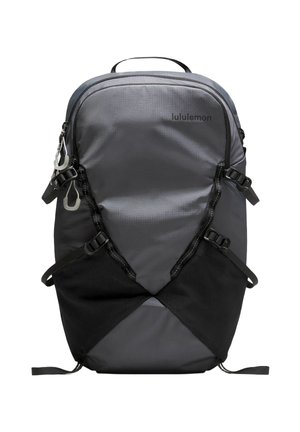 Grå og sort Lululemon-rygsæk med flere stropper, frontløkker og lynlåsåbnede rum, vist forfra på en hvid baggrund.