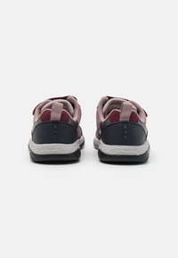 Para różowo-czarnych dziecięcych sneakersów widoczna z tyłu, z teksturowanymi białymi śródpodeszwami i pętlami do zakupu na kołnierzach pięty.