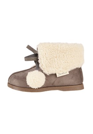Brown suede boot with a fluffy cream-colored shearling cuff and pom-pom detail. Features a flat sole and decorative gray ribbon.