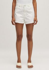 Witte denimshorts met een rafelige zoom, voorzakken en een getailleerde taille. Gecombineerd met neutrale sandalen, die een minimalistisch ontwerp tonen.