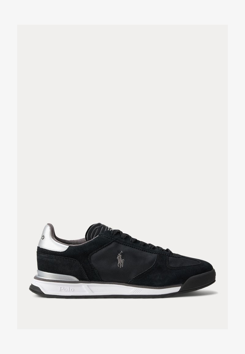 Svart lavt sneakersko med sølvhæl, strukturert sidestykke, Polo-logo, hvit mellomsåle og svart gummiyttersåle på ensfarget bakgrunn.