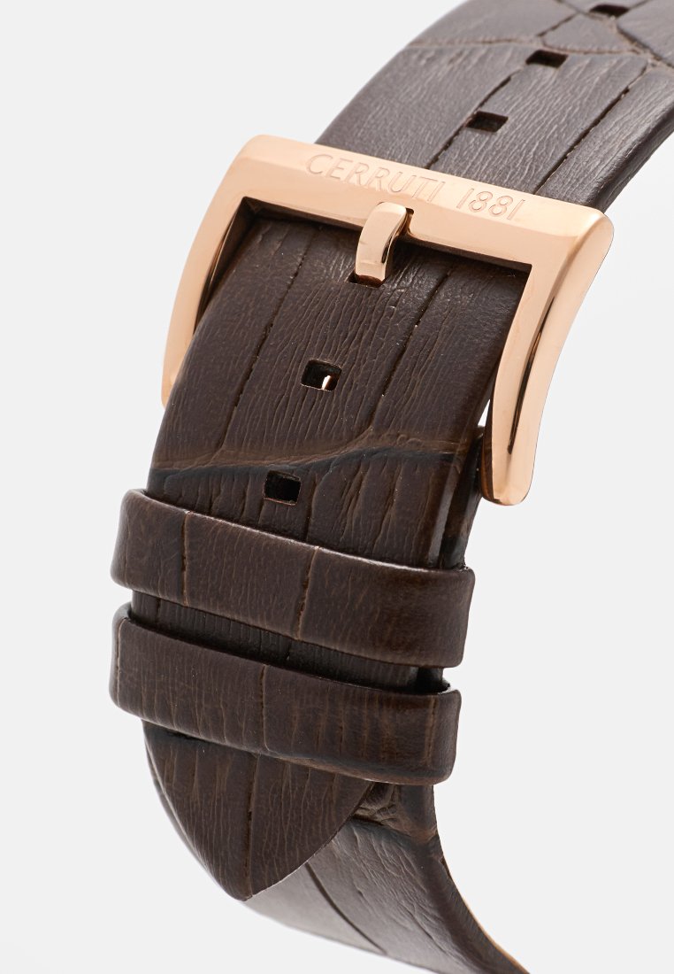 Bracelet de montre en cuir brun avec une boucle en rose gold gravée "CERRUTI 1881", présentant un motif texturé et des bords cousus.