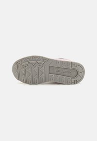 Suela de zapato de goma gris con patrones de dibujo en forma de triángulo, que presenta el logo de "Saucony" y una cresta texturizada para mayor agarre.