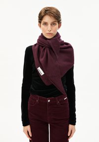 Écharpe bordeaux en tissu doux, drapée élégamment autour du cou. Texturée avec un motif subtil, étiquette de marque visible.
