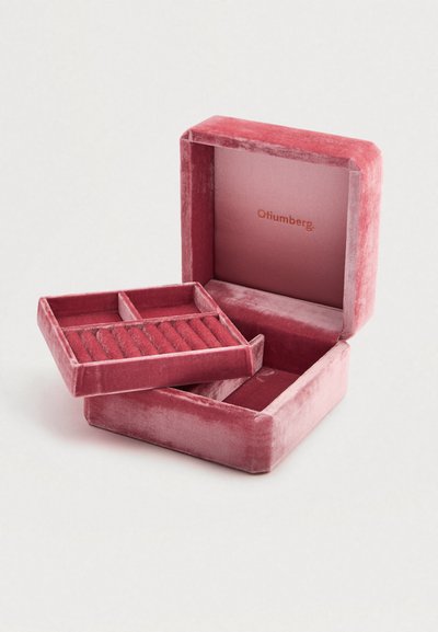 Βελούδινο κουτί κοσμημάτων σε απαλό ροζ, με αφαιρούμενο δίσκο διαχωρισμού και εσωτερικό με διακριτικό λογότυπο, αναδεικνύοντας πολυτελή υφή.