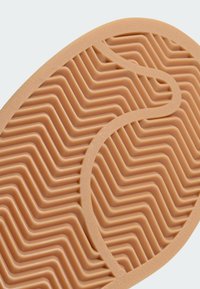 Gumeni potplat u boji tan s valovitim uzorkom i teksturiranim površinom za poboljšano prianjanje. Ojačan glatkim rubom.
