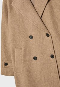 Double-breasted coat in light brown wool blend, featuring a structured lapel, two black buttons, and a side pocket. Textured finish.