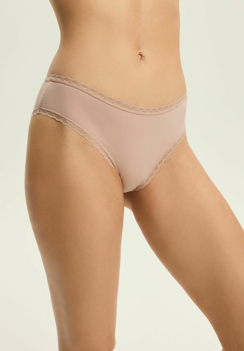 Nude majtki bikini z bawełny elastycznej, z falbaniastym koronkowym wykończeniem wzdłuż pasa i otworów na nogi, zapewniające gładką fakturę i minimalne zakrycie.