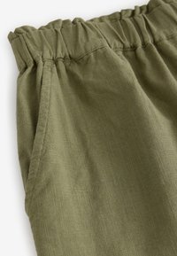 Olivgrönt, texturerat tyg med resår i midjan och sidofickor. Slät yta och mjuk fall, perfekt för vardagsbruk.