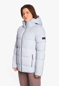 Giacca a vento leggera grigia chiara con cappuccio, con sezioni trapuntate, tasche con zip e un patch logo sulla manica. Tessuto liscio.