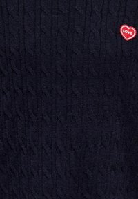 Tissu tricoté foncé avec un motif câble fin et un petit écusson en forme de cœur rouge avec le mot "LOVE" brodé en haut à droite.