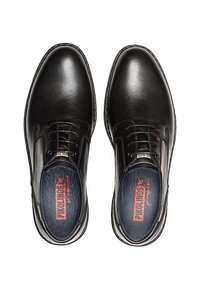 Une paire de chaussures de ville en cuir noir à lacets, avec des bouts ronds et des semelles intérieures bleues portant le logo rouge de Pikolinos, vue de dessus.