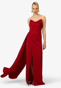 Rotes Satin-Abendkleid mit einem taillierten, trägerlosen Oberteil, asymmetrischer Drapierung und einem hohen Schlitz, das einen fließenden Schleppe hat.