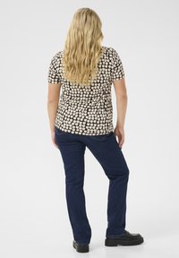 Kortärmad topp i ett brunt och svart rutmönster, i kombination med mörka jeans. Texturerat tyg med en avslappnad passform. Svarta skor.