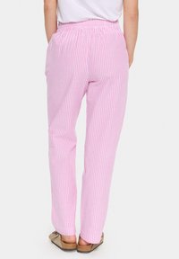 Lightweight, elastic waist pants in pink and white vertical stripes. Features side pockets and a straight fit. Worn with casual footwear.