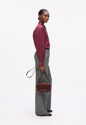 Burgundy quilted handbag with a silver hardware detail, paired with gray wide-leg pants and a matching burgundy button-up shirt.